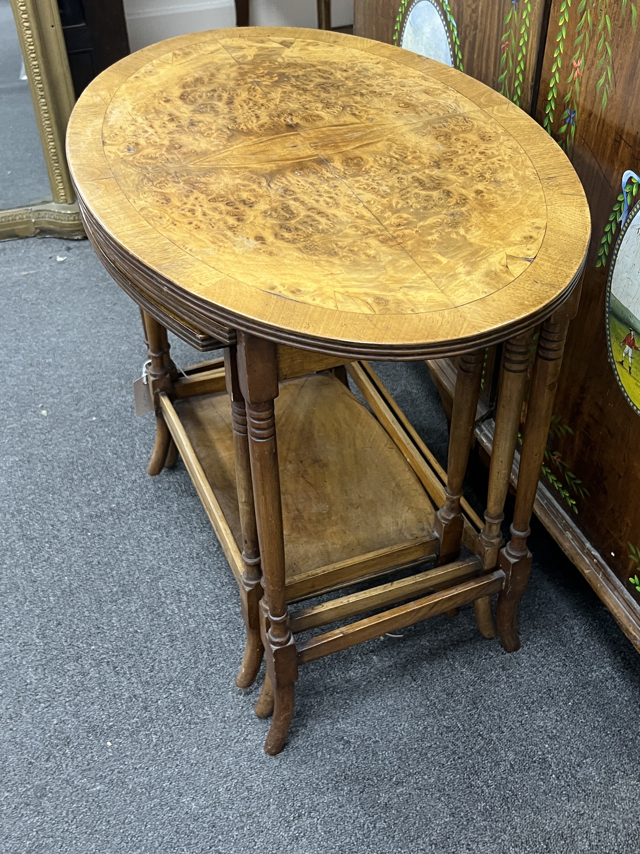A nest of three oval burr walnut teak tea tables, width 61cm, depth 41cm, height 52cm